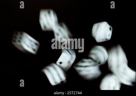 Dice rolling across a black background Stock Photo