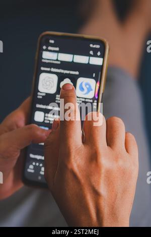 The person's finger is touching the screen, seemingly selecting an AI app. Stock Photo