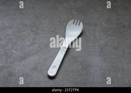 Two White Plastic Utensils on a Smooth Gray Surface Stock Photo