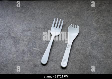 Two White Plastic Utensils on a Smooth Gray Surface Stock Photo