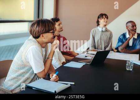 Young students in a contemporary classroom are engaged in a lively discussion. They are collaborating, learning, and sharing ideas in an innovative ed Stock Photo