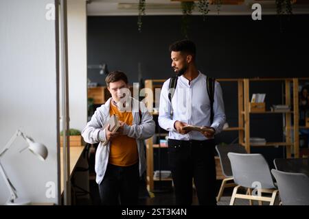 Young man with Down syndrome and his teacher talking while walking down the school hallway. Stock Photo