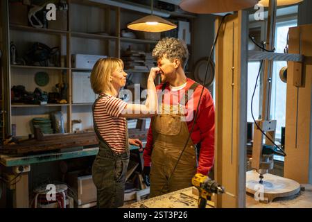 Cheerful family of carpenters having fun and joy in workshop, playful moment during work break Stock Photo