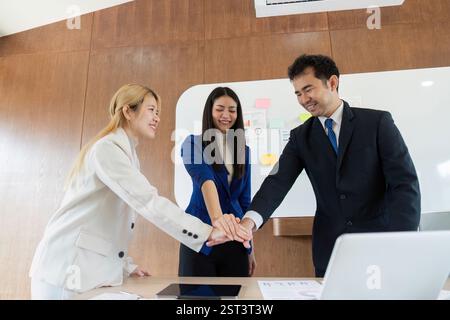 Diverse business team celebrating success with a group huddle in a modern office environment. Stock Photo
