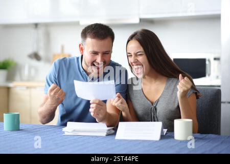 Excited couple checking bill in the kitchen at home Stock Photo