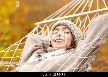 Happy woman resting on hammock looking at you in autumn holiday in a forest Stock Photo