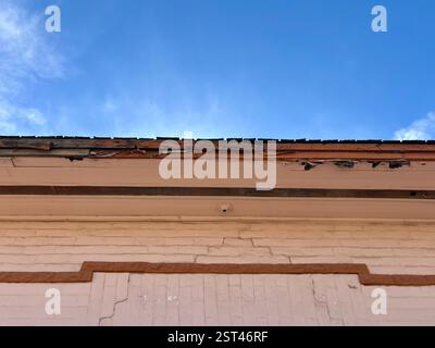 Deteriorating western building facade, roof under blue sky Stock Photo