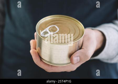 opening a tin can. Tin can with ring in male hand. Close up an empty can for design and text. Copy Space Stock Photo