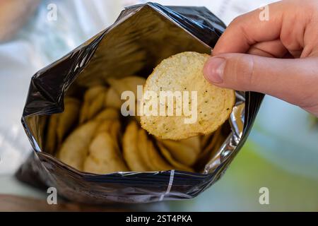 Crispy potato chips in aluminum metal bag package. The concept of an unhealthy food and lifestyle. Bag of Potato Chips Stock Photo