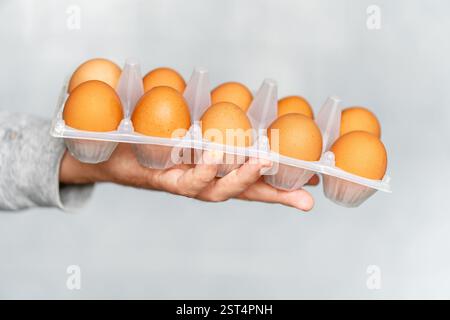 Male hands holding cardboard egg box full of chicken eggs in the kitchen on blue background Stock Photo