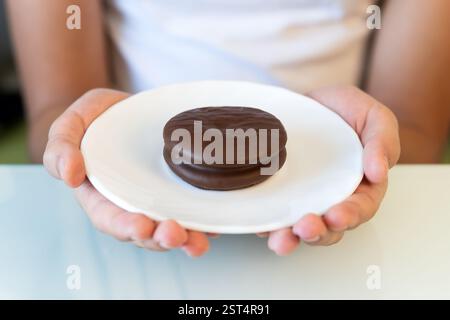 Tasty sweet choco pie in a white plate on the girl's hands. Stock Photo