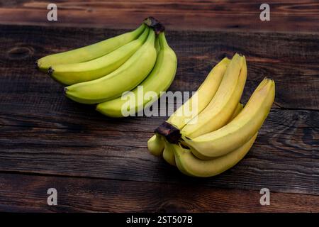 Green, yellow bananas arranged in a row on wooden table. ripe and unripe banana Stock Photo