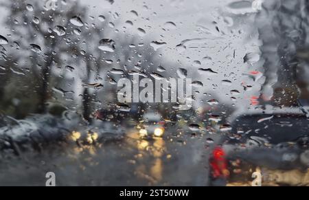 Melted snow and rain drops on the windshield of a car. Blurred outdoor view, winter season sleet as seen out of vehicle window Stock Photo