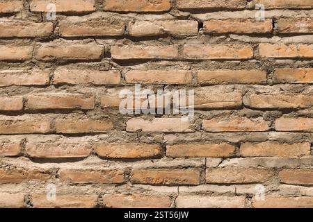 A textured background of a red brick wall with ceramic tiles featuring intricate patterns. Stock Photo