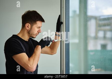 Professional repairman adjusting white pvc windows in modern building. Construction worker installing plastic window in new home. Concept of repair an Stock Photo