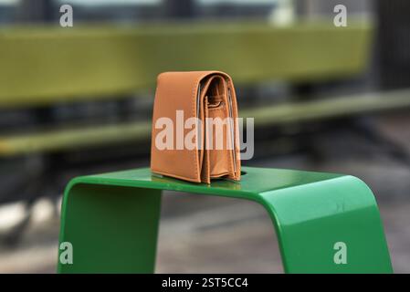 Stylish brown wallet in leather placed on a green metal surface in an urban outdoor scene, fashion and style concept Stock Photo