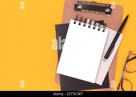 Workspace with blank notepad mockup, eyeglasses and stationery on a yellow background. Creative layout with place for text. Stock Photo