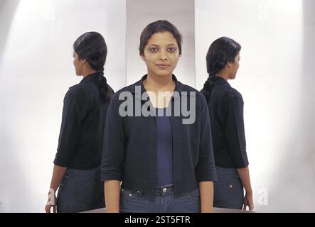 Indian woman with two mirror reflections dressed in jeans and a jacket Stock Photo