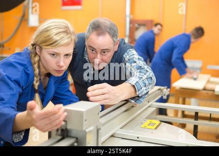 teacher explaining how to use machine in a woodwork class Stock Photo