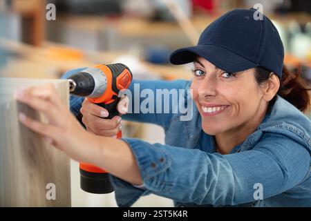 cheerful woman using a cordless screwdriver Stock Photo