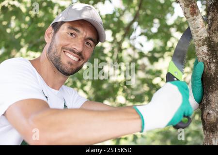 smiling farmer pruning branches of fruit tree Stock Photo