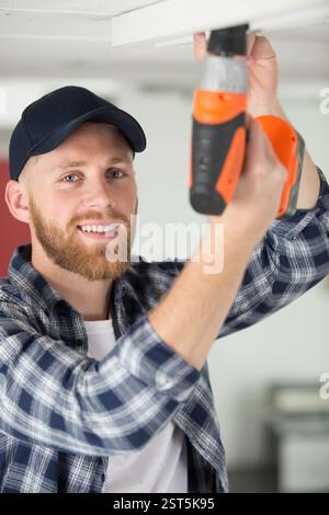 workman using cordless screwdriver on the ceiling Stock Photo
