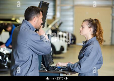 mechanic training female apprentice to use computerised equipment Stock Photo