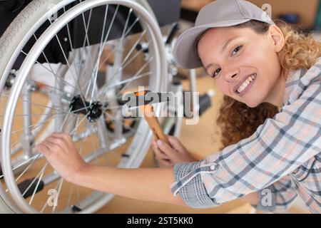 female mechanic using hammer on wheelchair wheel Stock Photo