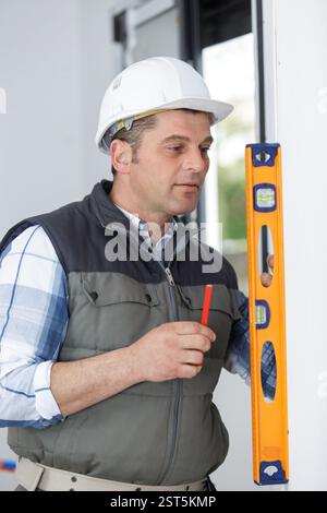 mature builder using spirit level Stock Photo