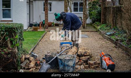 A workman rebuilding a brick and flint wall reusing old bricks. Stock Photo