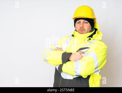 a man wearing a yellow working winter jacket and a yellow safety helmet . High quality photo Stock Photo