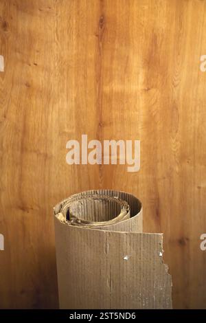 Rolled corrugated cardboard paper against wooden wall, selective focus Stock Photo