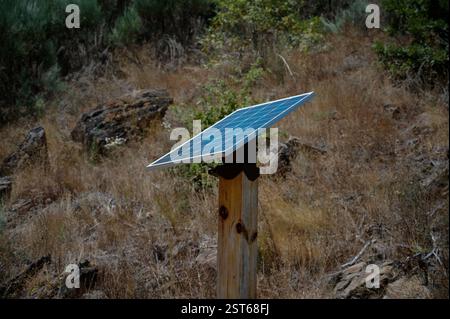 A small off-grid solar panel mounted on a wooden post in the dry landscape of the Mondego Walkways Stock Photo