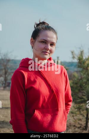 Young woman in red hoodie enjoying outdoor nature in autumn. Stock Photo