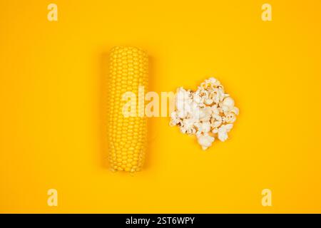 A minimalist composition featuring an ear of corn and freshly popped popcorn on a bright yellow background, symbolizing the transformation from corn Stock Photo