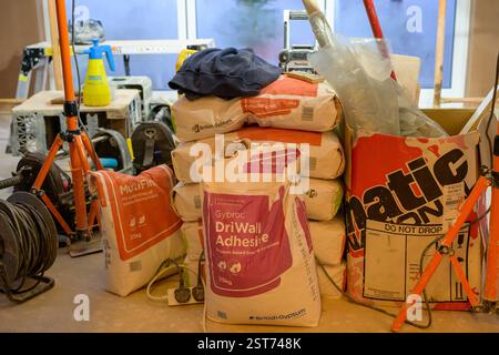 building materials and tools displayed on a construction site, showcasing items like adhesive bags and work tools against a prepared background Stock Photo