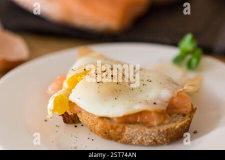 A slice of bread with lightly salted red fish and a cooked egg for breakfast. Stock Photo