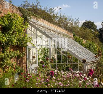 Lean-to greenhouse with bright flowers outside in the walled garden at Beningbrough Hall Stock Photo