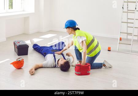 Worker Administers First Aid with Workplace Kit to Colleague After Accident Stock Photo