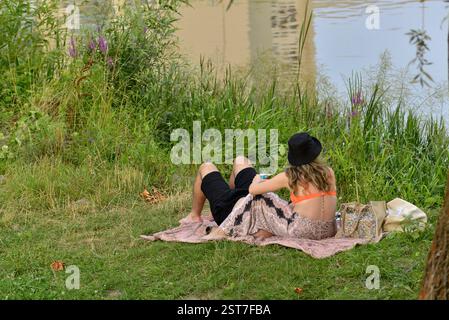 Young couple relaxing on the banks of the river on a summer's day Stock Photo