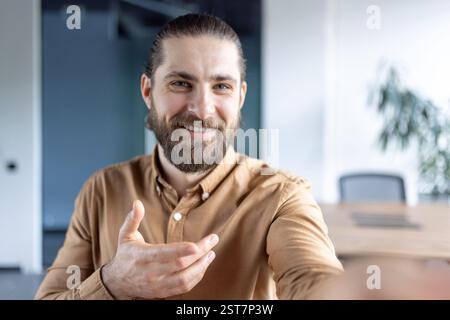 Webcam view, man inside office at workplace using smartphone app for video call, talking to colleagues and partners while sitting at desk. Stock Photo