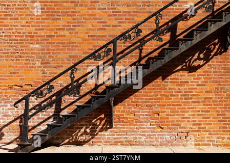 Black metal staircase with red brick wall background. Stock Photo