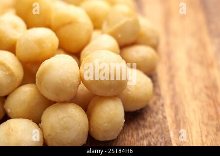 Macadamia nuts on wooden surface. Natural nutritious snack with healthy fats and nutrients. Close-up Stock Photo
