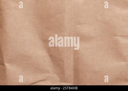 Wrinkled brown kraft paper with creases and folds. Sustainable packaging material. Crumpled surface. Wrapping sheet. Top view. Abstract background Stock Photo