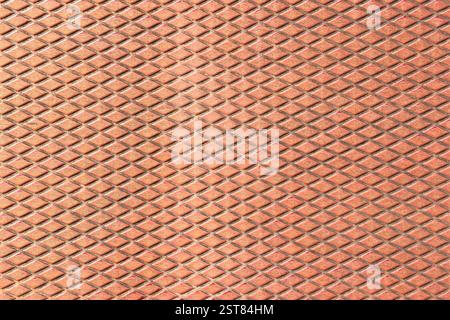 Rusty metal sheet with a repeating diamond pattern. Industrial building exterior cladding. Weathered structure. Corrosion and aging signs. Abstract ba Stock Photo