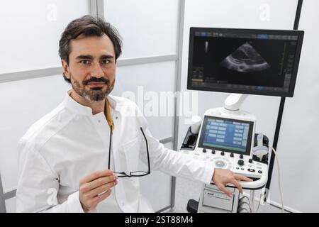 Handsome male doctor using modern ultrasound scanner for ultrasonography. Ultrasound or ultrasonic diagnostics Stock Photo
