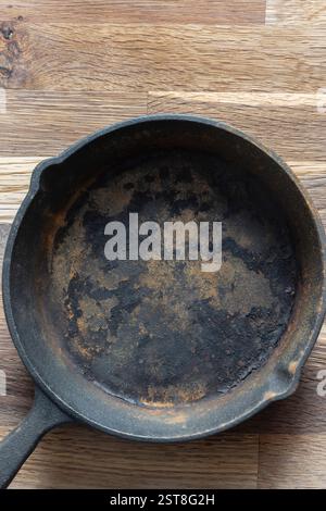 Old rusty cast iron frying pan background. On a wooden chopping cutting board. Stock Photo