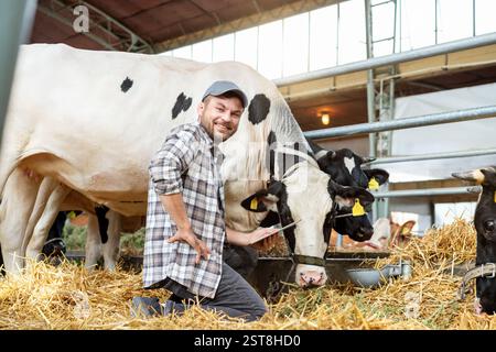 Male livestock farmer smiling and holding digital tablet while inspecting cows at cattle farm Stock Photo