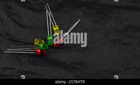 collection of red, green, and yellow LED diodes arranged on a dark crinkled paper surface, highlighting the different colors and detailed structure of Stock Photo