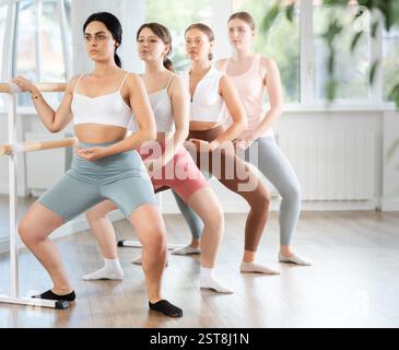 Young ballerinas practicing demi plie at barre in choreography studio Stock Photo